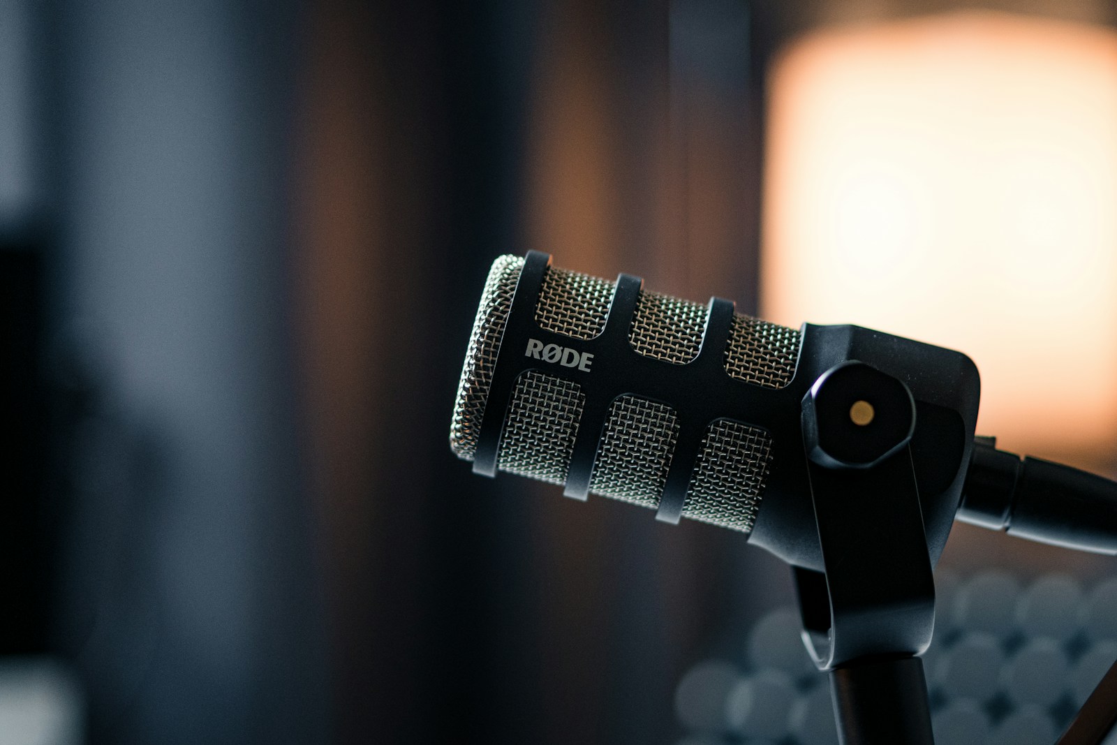 Close-up of a Røde podcast microphone with warm studio lighting in the background