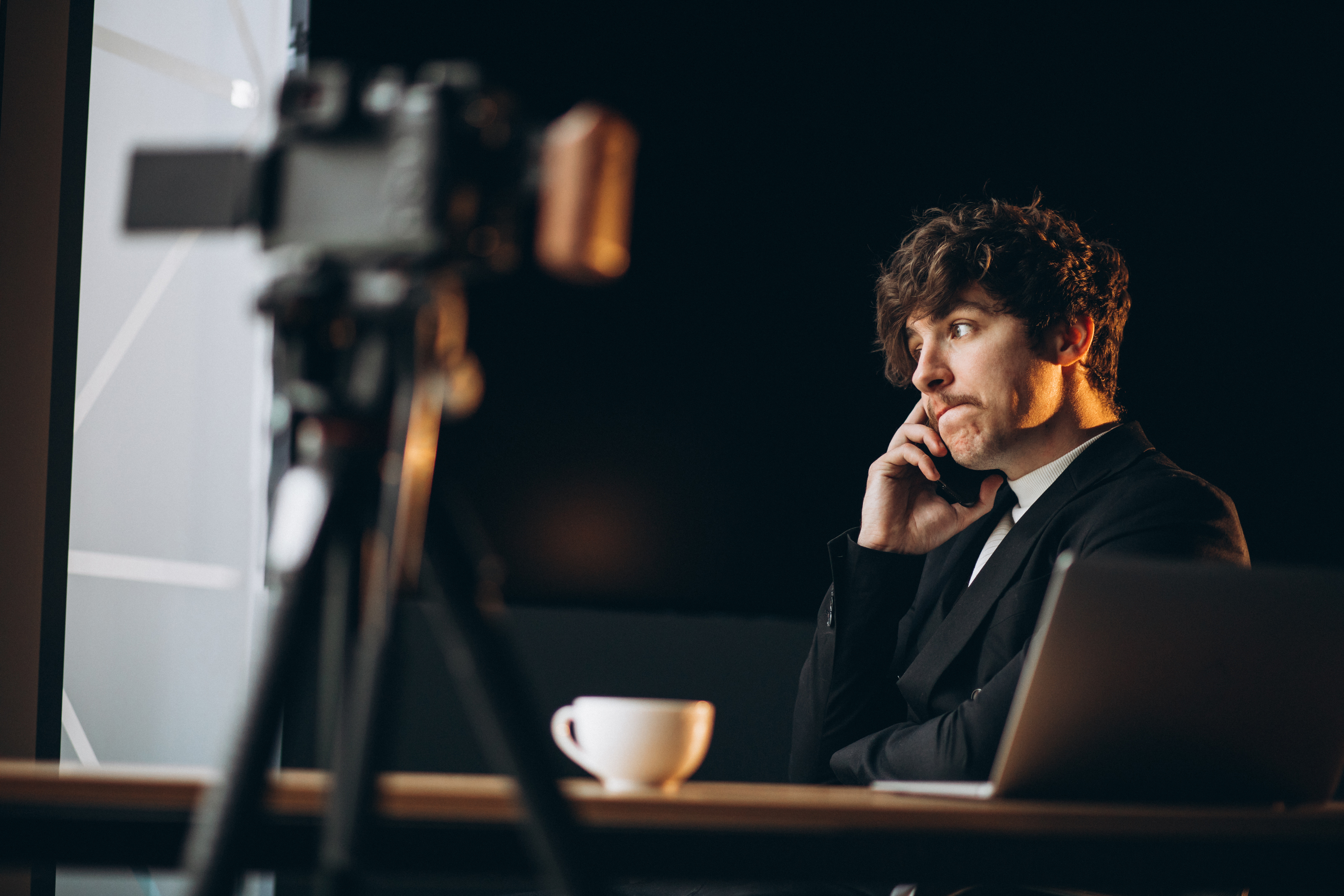 Content creator in dark studio with camera and laptop