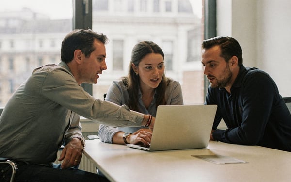 Three marketing colleagues reviewing an older brand film on a laptop in a bright London meeting room