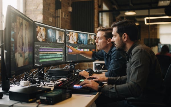 Two video editors reviewing colour-graded footage across several monitors in a London post-production edit suite